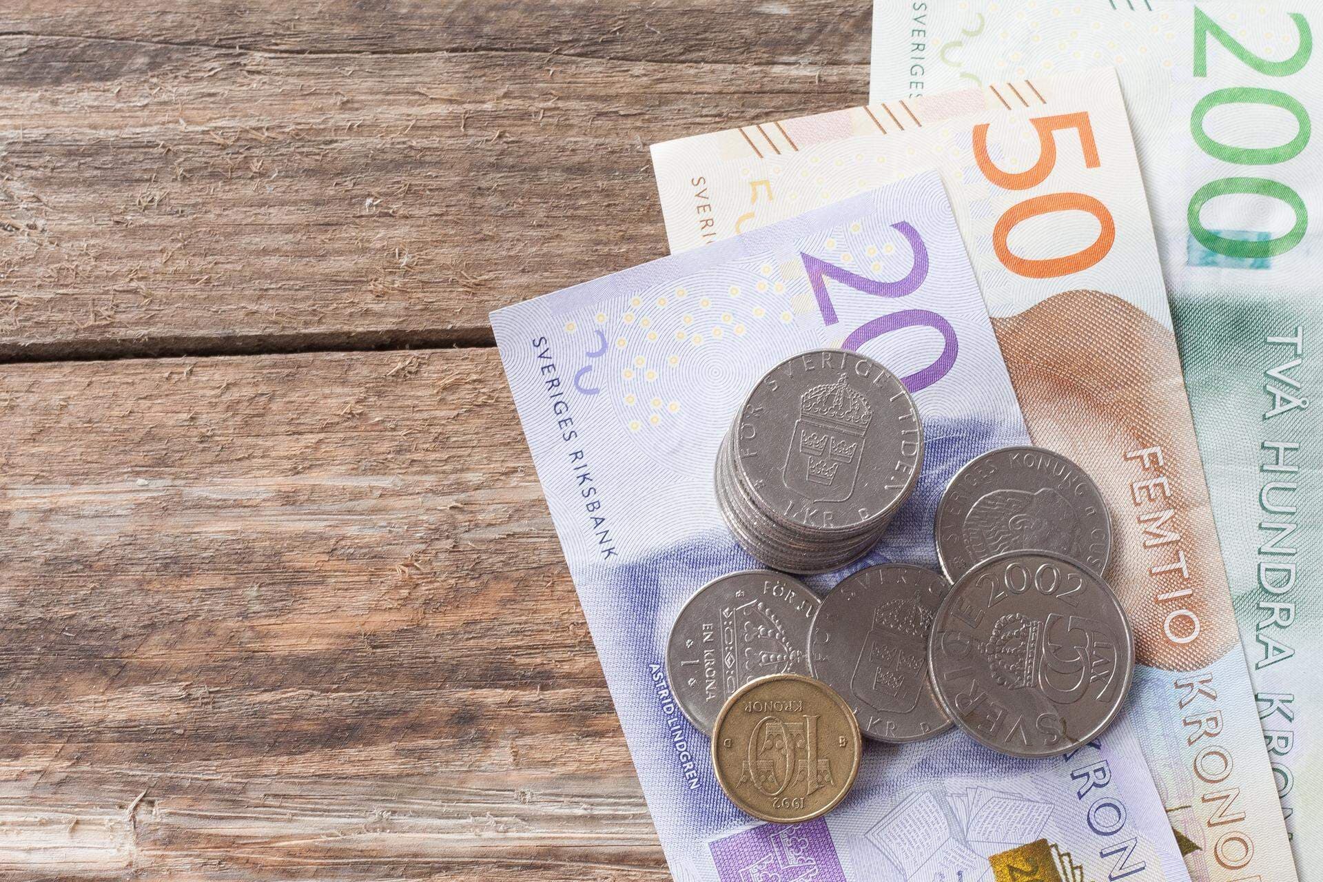 Svenska sedlar och mynt mot en bakgrund av grovt trä